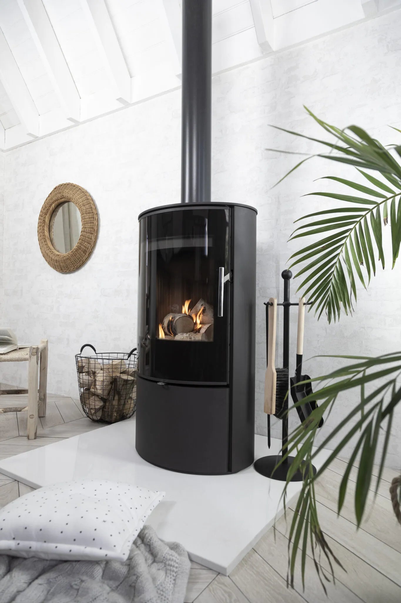 Cylindrical logburner in a very white room. Stove is an Arada Lagos and is lit