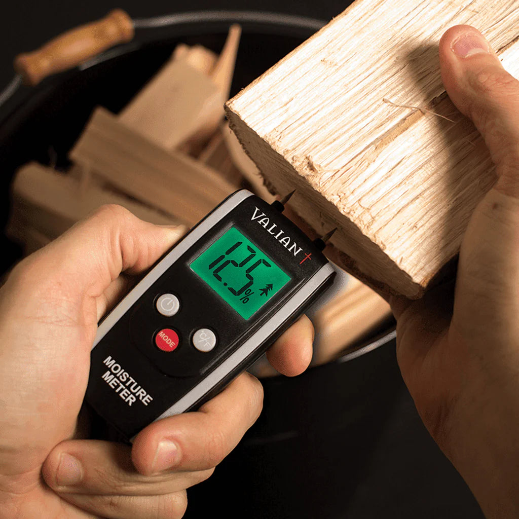 Moisture meter being inserted into a block of wood for testing if dry enough for a Hetas approved woodburner