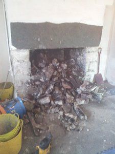 a lot of rubble cascading out of a fireplace recess in a stone property