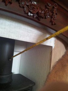 tape measure showing distance from wood to stove pipe