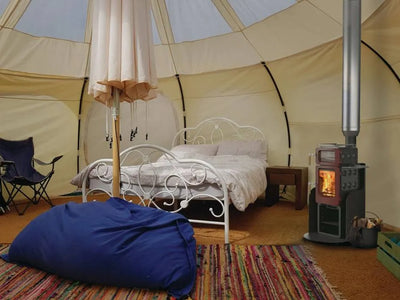wood stove in a yurt with a bed glamping