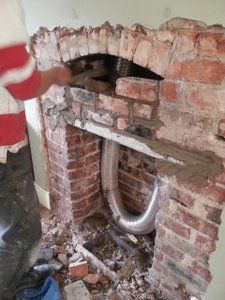 a stove installer fits a new lintel below the arch for a wood burning stove installation